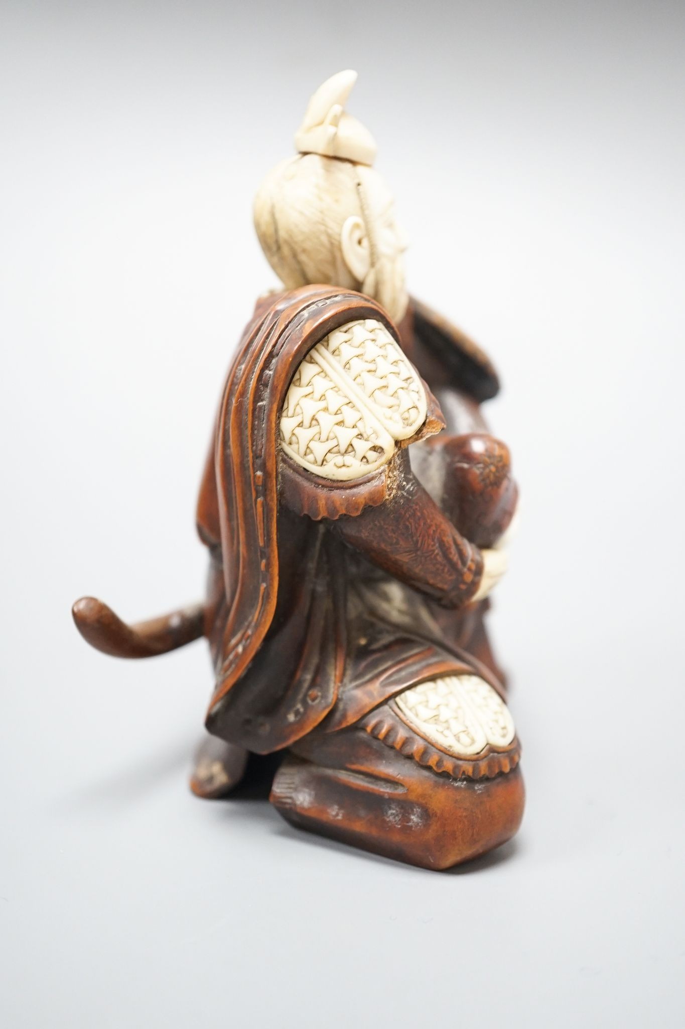 A Japanese wood and ivory okimono of a kneeling samurai holding a baby, Meiji period, unsigned, 12cm